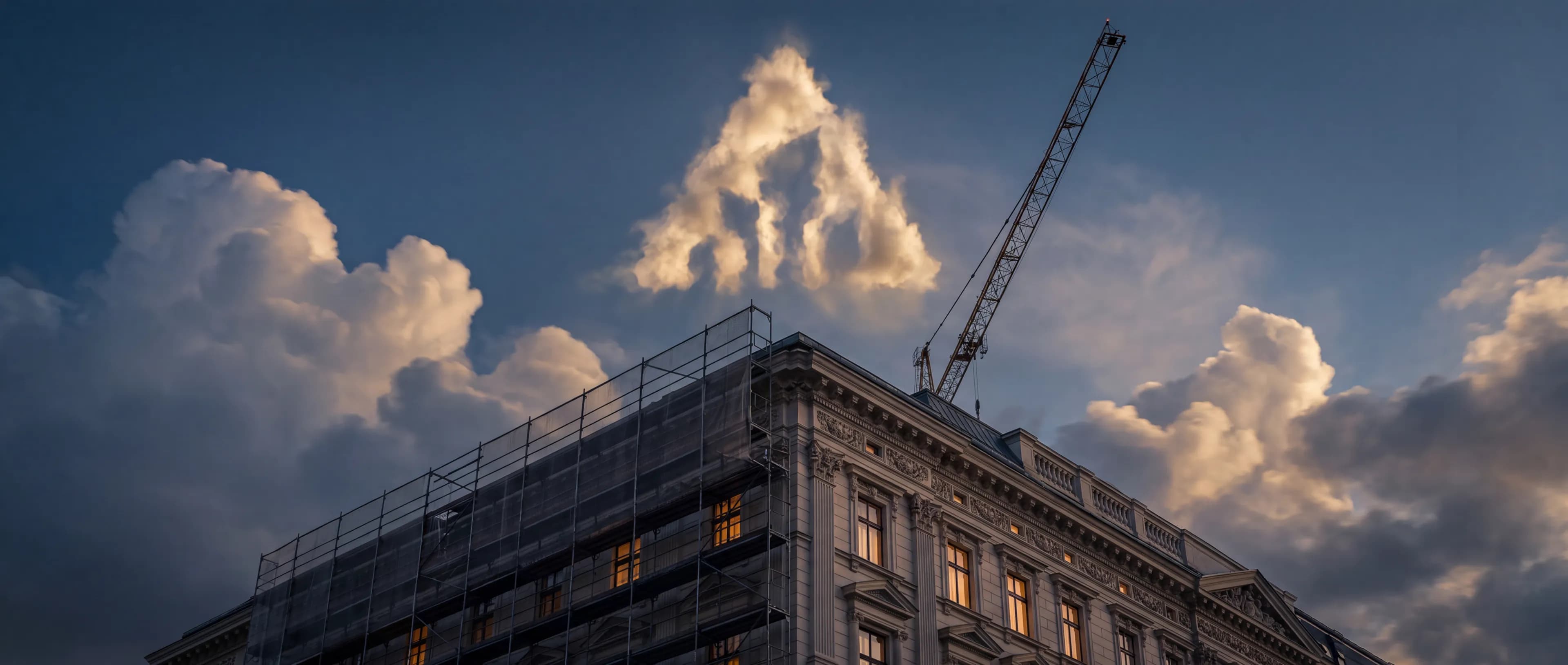 A Gründerzeit building in Vienna under refined restoration at dusk, the Revide emblem formed in the clouds above